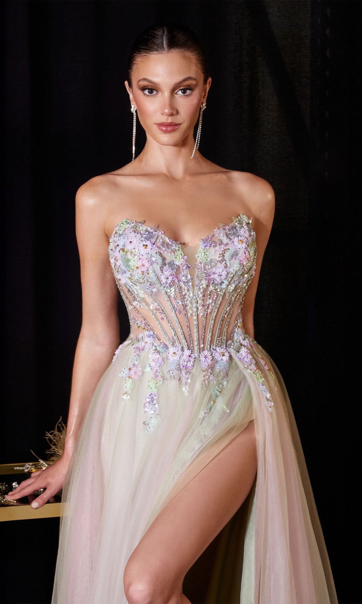 Model wears the Ladivine CD2418 Long Prom Dress with an embroidered corset bodice, floral detailing, tulle A-line skirt, and high slit, posing against a dark background.